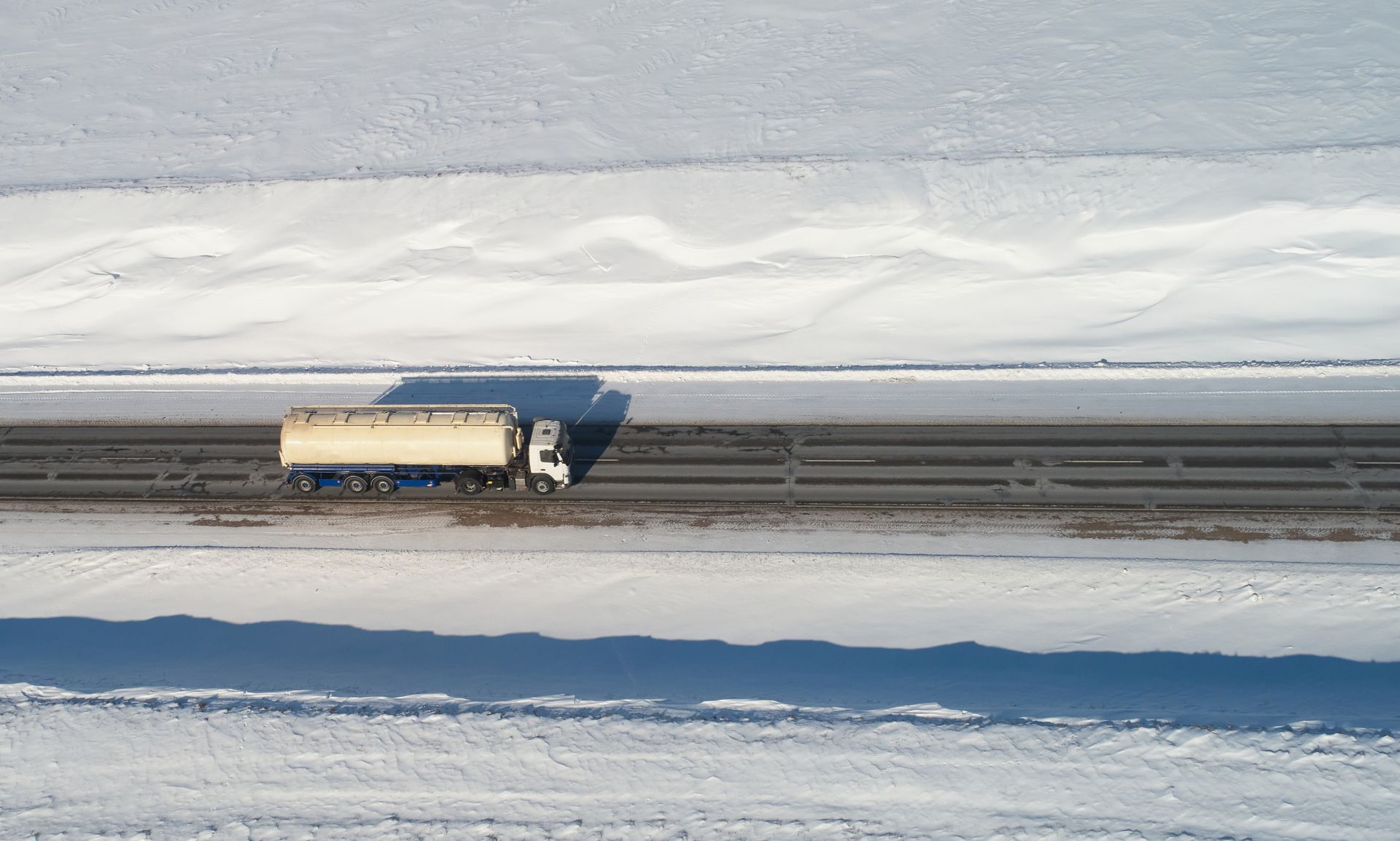 Heizöltankwagen fährt auf verschneiter Landstraße im Winter