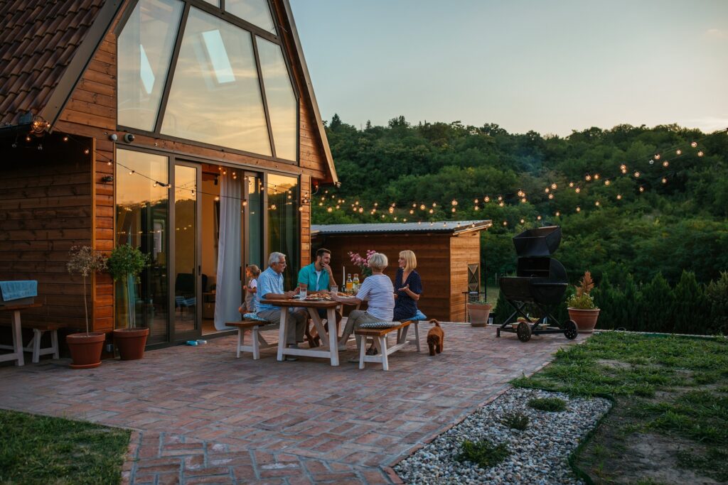 Familie sitzt abends auf Terrasse unter Lichterkette | Petroleum
